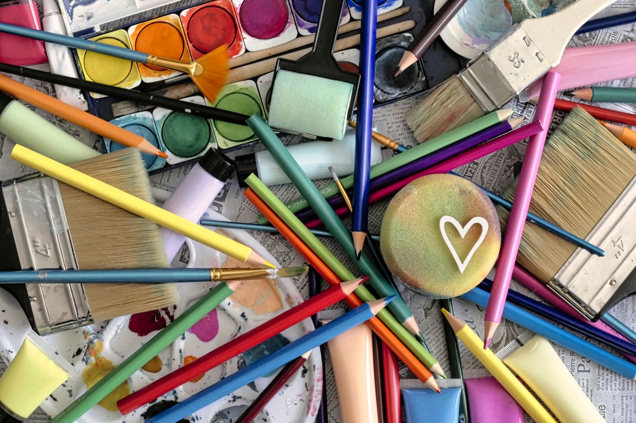 services-04 A vibrant assortment of art supplies including paints, brushes, and pencils, featuring a heart motif.